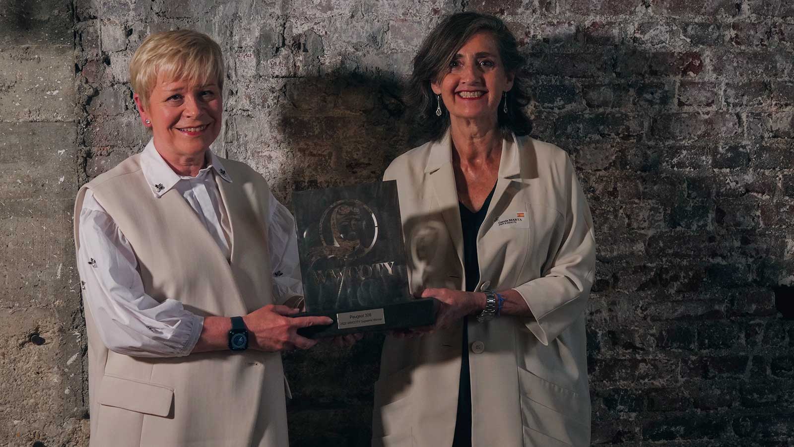 Linda Jackson recibe el premio de manos de la presidenta ejecutiva del WWCOTY, Marta García
